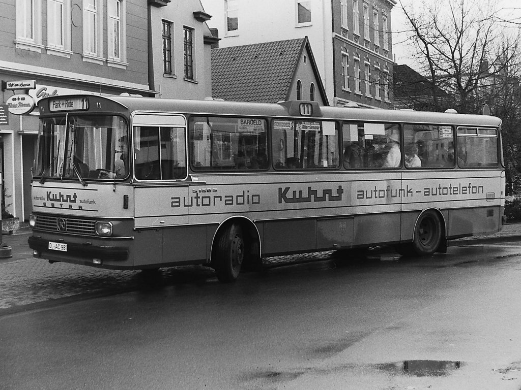Wagen 11, OL-AC 981, EZ: 1976. Mit der Anschaffung von acht Linienbussen des Typ S 130 S des Herstellers SETRA-K�SSBOHRER kehrten die Setra-Busse, die einst auf Grundlage der Patente von Theodor Pekol konstruiert wurden nach Oldenburg zur�ck. Allerdings hatte Setra auf Basis ihrer 100er-Reisebusserie den Sprung in das Linienbussegment versucht. Man sah es den Fahrzeugen nicht nur an, dass ihre Fahrgestelle eigentlich f�r Reisebusse entwickelt waren, man erlebte es auch im t�glichen Gebrauch. Sowohl Fahrer als auch Fahrg�ste mussten Kompromisse und Einschr�nkungen in Kauf nehmen, die der Spagat eines Linienbusses auf Basis eines Reisebusses mit sich brachte. Und so passten die Busse denn auch nicht in das mittlerweile bekannte und gewohnte Bild der V�V-Standardlinienbusse. Au�erdem verabschiedete man sich mit der Einf�hrung der neuen Busse auch vom alten, jahrelang genutzten Farbton  Pekolgr�n . Die neue Lackierung war ein sattes leuchtendes Gr�n. Was die Kennzeichen anbelangte schloss man zwar an den Wagen 150 an, bei der Nummerierung der Busse begann man nun aber bei der Betriebsnummer 11.
Das Bild entstand im November 1981 an der HS Elisenstra�e. Der Bus war zum Zeitpunkt der Aufnahme im Park & Ride Verkehr. Im August 1982 �nderte KUHNT die Werbung. Der Bus trug nun ein �hnliches Design mit beigefarbener Schrift auf braunem Grund.