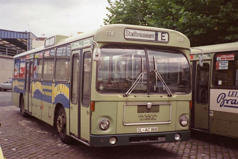 Wagen 126, OL-AC 866, EZ: 1973. Hier sehen wir einen alten Bekannten, den ich bereits vorgestellt hatte. Allerdings mit einem Bild auf dem der Bus in einiger Entfernung abgebildet ist. Hier nun eine Aufnahme aus dem September 1980. Diese Version der HULLMANN WEIZENKORN-Werbung war bereits die zweite an diesem Bus. In der ersten Variante war das Werbeband in einem tiefen Dunkelblau gehalten. Die �nderung erfolgte zwischen 1977 und 1978. Der Bus steht auf dem Abstellplatz f�r Reservebusse, wie er urspr�nglich angelegt war. Der Umbau erfolgte wenige Monate sp�ter. Neben Wagen 126 steht Wagen 109, dahinter Wagen 15. Wagen 126 geh�rte zur sogenannten  Dortmunder Serie . Die Busse waren eigentlich f�r Dortmund bestimmt gewesen und dann von Pekol abgenommen worden. Im Inneren der Fahrzeuge war dieser Umstand deutlich zu erkennen. Wagen 126 trug bis zu seinem Ausscheiden neben der eigenen Betriebsnummer sogar noch die f�r Dortmund vorgesehene Nummer  1237 . Aber auch �u�erlich gab es Unterschiede. Die fehlende Heckrundfenster hatte ich bereits fr�her angesprochen, auch die Nebelscheinwerfer. Im Vergleich mit dem vorherigen Bild von Wagen 117 kann man zudem Unterschiede im Zielschild erkennen. Bei den Dortmunder Bussen war die Trennung zwischen Liniennummer und Fahrziel schwarz. Die Oldenburger Busse hatten diese Trennung in wei�. 