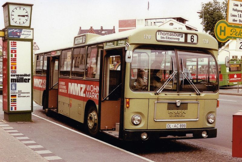 Wagen 129, OL-AC 899, EZ: 1973. Diese Aufnahme, die Werner Striepling im Juni 1978 machte, ist in mehrfacher Hinsicht betrachtenswert. Sie zeigt nicht nur Wagen 129 mit seiner ersten Werbung f�r MMZ-WOHNMARKT, sondern ist auch eine der wenigen Farbaufnahmen, wenn nicht die einzige bis jetzt, die einen Bus der  Dortmunder Serie  mit offenen T�ren zeigt. Damit k�nnen wir einen kleinen Blick auf die Innenfarbe erhaschen. In den Bussen der OVB Pekol war der Innenraum in hellen und dunklen Graut�nen gehalten. Hier ist deutlich eine bronzefarbene Lackierung der T�ren zu erkennen. Auch die roten Haltestangen, die hier leider nicht zu sehen sind, hoben sich deutlich in den Bussen ab, zumal Pekol die Busse mit zus�tzlichen Stangen ausstattete, die nat�rlich wieder die eigene Farbe hatten. Im Hintergrund rechts ist einer der ersten MAN SL 200 zu sehen. Das der Bus auf der Linie 5 eingesetzt ist, legt die Vermutung nahe, dass es sich um einen der Busse handelt, die einen Sp�tdienst bedienten. Wenden wir uns dem linken Bildrand zu. Leider fast vollst�ndig durch die noch recht neue Werbeeinrichtung verdeckt, steht hier ein S 130 S. Der aufmerksame Besucher wird feststellen, dass ich bisher hier einen Setra mit wei�er Frontwerbung nicht gezeigt habe. Es handelt sich um Wagen 16 mit seiner ersten Version der JUNO-Werbung. An der Front und an einer Seite war zudem Werbung f�r CARL-WILH. MEYER. Und zuletzt zu dem bereits angesprochenen Werbetr�ger. Diese Weiterentwicklungen der klassischen Litfa�s�ule wurden, wenn ich mich richtig erinnere, Mitte der 70er Jahre an der zentralen Umsteigestelle aufgestellt. Nachts beleuchtet, zwangen sie die Fahrg�ste den sch�nen breiten Bereich direkt am Bordstein zu verlassen und sich den Weg zu ihrem Anschlussbus zu bahnen. Meist unter Verwendung des Radweges, worauf der typische Oldenburger Radfahrer, nat�rlich ohne Licht unterwegs, in der Regel mit lautem Klingeln reagierte. Der versierte Zweiradprofi, der diese Strecke regelm��ig fuhr, wich dann in der Regel sofort auf den Fu�weg aus und warf dabei gleich mal einen Blick in die Schaufenster von Hertie. Oder man quetschte sich als Fahrgast zwischen S�ule und Bus hindurch, wenn man denn �berhaupt vern�nftig aussteigen konnte, denn je nachdem wie die Busse hielten, standen sie manchmal mit der hinteren T�r, so wie hier zu sehen, direkt vor so einem Hindernis. F�r uns hat diese spezielle S�ule allerdings noch einen Dienst parat. In ihr prangt ein Plakat f�r das EUROPAM�BELHAUS M�LLER. Somit bekommen wir einen leichten Eindruck des Aussehens von Wagen 165. Der trug diese Werbung nach seiner Indienststellung 1972. Neben Wagen 129 trug auch Wagen 130 zun�chst die auf dem Bild gezeigte Werbung f�r MMZ-WOHNMARKT. Und wer weis, vielleicht bekommen wir ja an dieser Stelle auch noch mehr von Wagen 16 zu sehen, mal abwarten ...